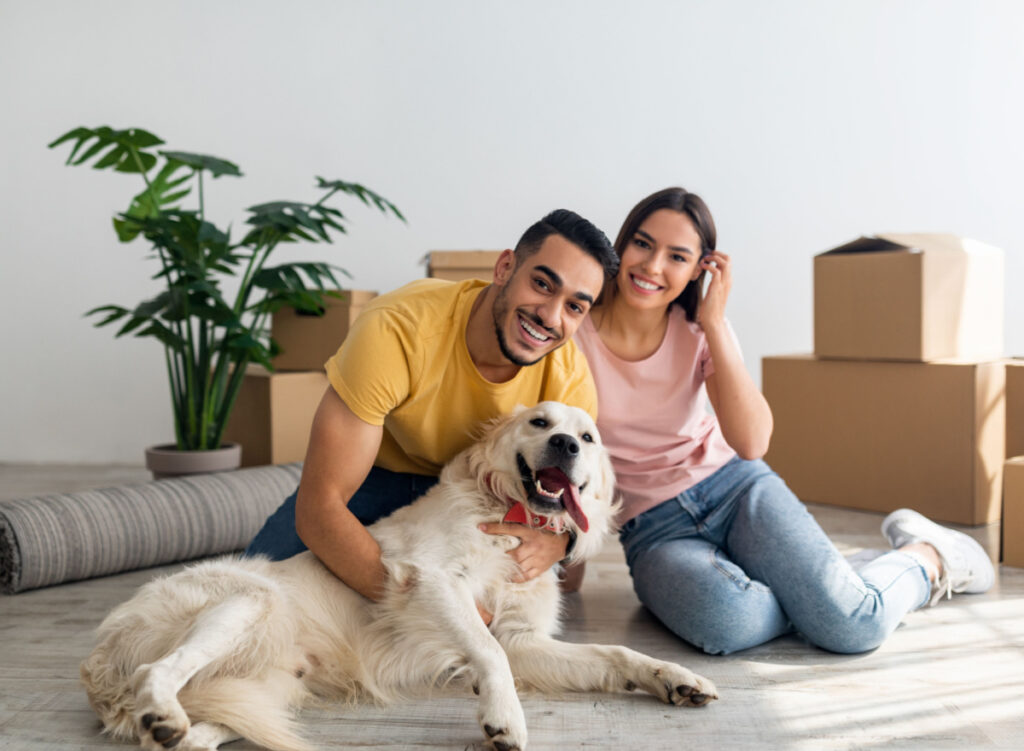 people moving into an apartment posing with their dog.