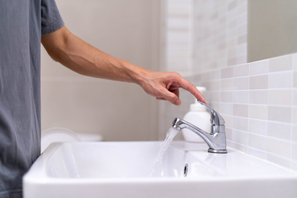 Turning off the tap in a bathroom to save water.