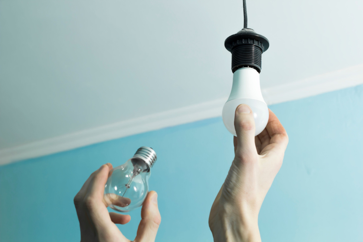 Changing an incandescent lightbulb to an LED one to save money on utilities.