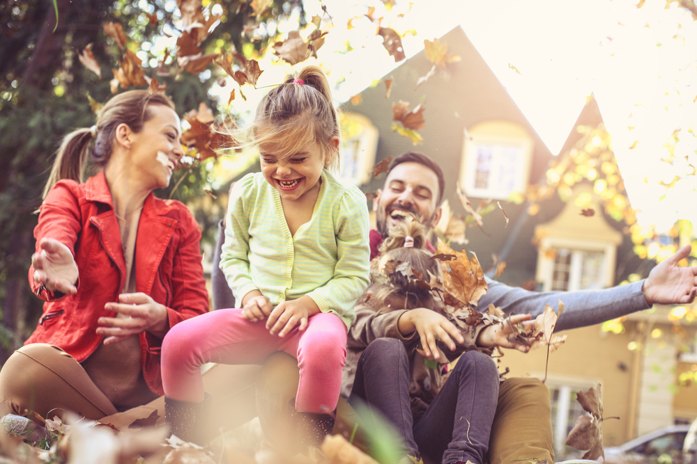 family playing in the autumn leaves