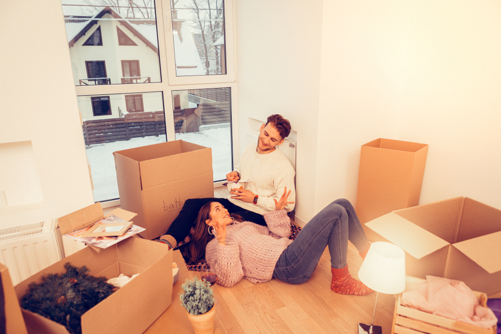 Couple lounging inside their new apartment after moving in the winter.